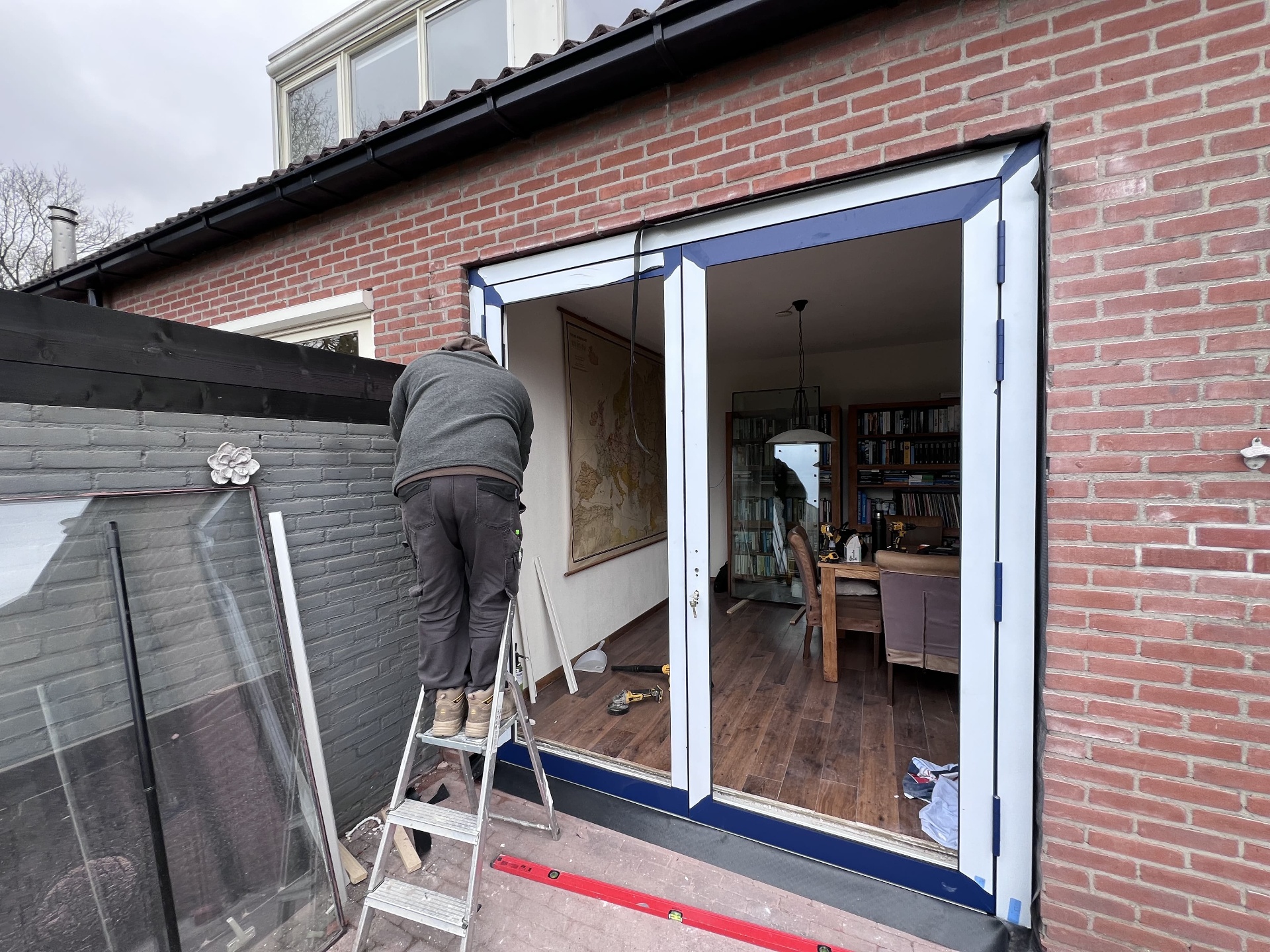 Kozijn van openslaande deuren wordt waterpas gesteld in de gevelopening